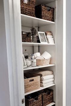 an organized linen closet with baskets and towels