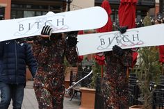 two snowboarders walking down the street with their boards on their heads and arms