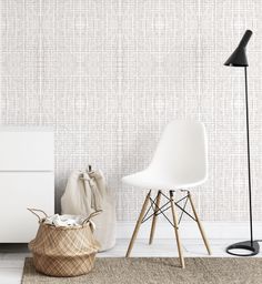 a white chair sitting next to a lamp on top of a wooden floor in front of a wall