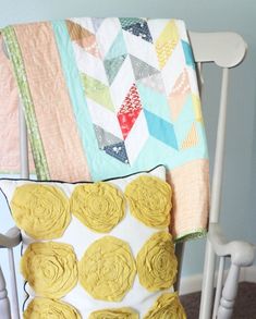 a white rocking chair with yellow flowers on the cushion and a quilted throw pillow