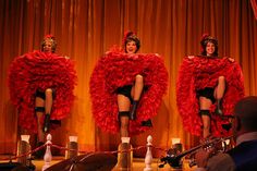 three women dressed in red are performing on stage