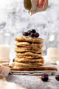 a stack of pancakes with blueberries and syrup being drizzled on top