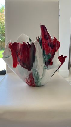 a red and white vase sitting on top of a table