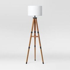 a wooden tripod floor lamp with a white shade