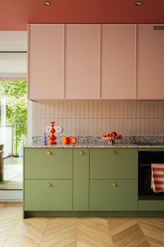 a kitchen with green cabinets and pink walls