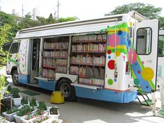 a white and blue bus parked in front of a building filled with lots of books