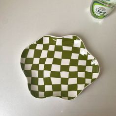 a green and white checkered plate next to a can of cleaner