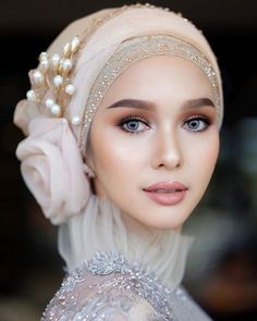 a woman wearing a head scarf with pearls on it's head and an elaborate veil over her head