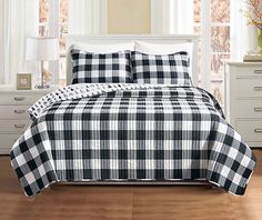 a black and white checkered comforter set on a bed in a room with windows