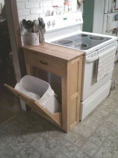 a kitchen with an oven, stove and trash can in the corner on the floor