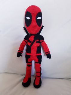 a crocheted deadpool doll sitting on top of a bed