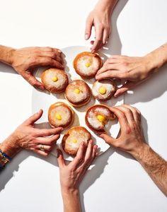 several hands reaching for pastries on a plate