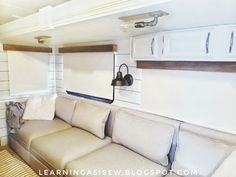 a couch with pillows and a lamp on the wall in a living room next to cabinets