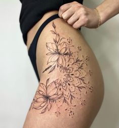 a close up of a person's thigh with tattoos on it and flowers in the middle