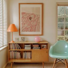 a living room with a chair, bookshelf and a painting on the wall