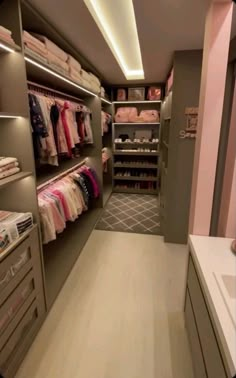 a walk in closet filled with lots of clothes and drawers next to an open door