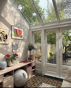 the sun shines through the glass roof in this room with furniture and artwork on the walls