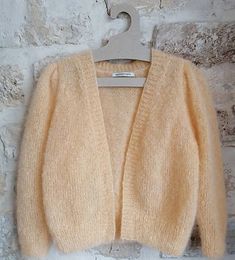 a cardigan sweater hanging on a brick wall