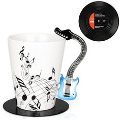 a coffee cup with music notes on it and an electric guitar next to it in front of a record