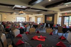 a banquet room with tables and chairs set up for an event or function, including red napkins on the table