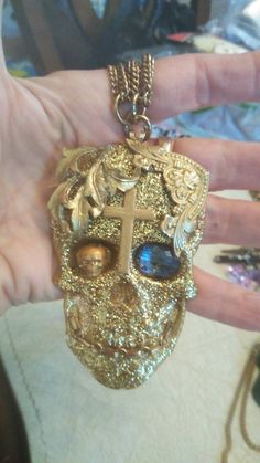 I made this resin skull. It was filled with super fine glitter which you can see on the back. I painted it gold added pieces of vintage jewelry surrounded by a gold painted metal cross. Has a gold chain grill in his smile. A small gold painted metal skull in his eye and a pretty blue glass bead in the other eye. It hangs on a multi-chain. It is saying SkullVisions by Mars on the back and the number. Gold Skull Necklace, Halloween Eye Makeup, Metal Skull, Gold Skull, Metal Cross, Skull Necklace, Eye Makeup Tutorial, Gold Paint, Metallic Paint