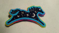 an embroidered brooch with a black horse on it's back and stars in the sky