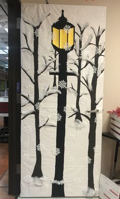 an art project is displayed on the wall in front of a light pole and snow covered trees