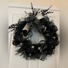 a wreath with black and silver decorations hanging on a door