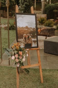 an easel with flowers on it and a photo