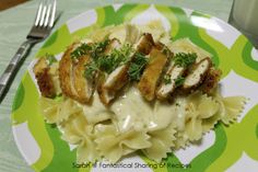 chicken with creamy italian sauce and pasta on a green and white plate next to a fork