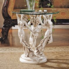 a glass topped table with statues on it in front of a couch and coffee table