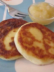 two pancakes on a blue and white tablecloth with a bowl of fruit next to it