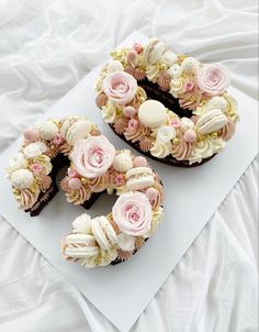 two cupcakes decorated with pink and white flowers on top of a sheet of paper