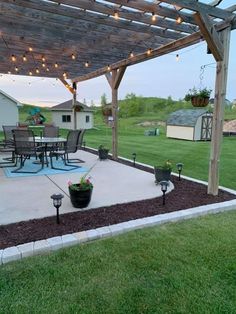 an outdoor patio with lights on the ceiling and potted plants in the ground next to it