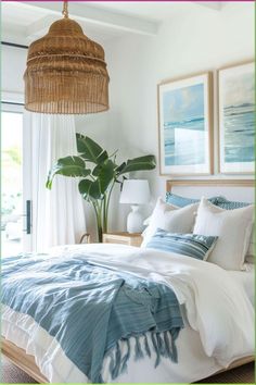 a bed with blue and white comforter in a bedroom next to a window, potted plant and wicker chandelier