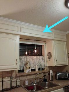 a kitchen area with sink, microwave and counter top in front of the window that has curtains on it