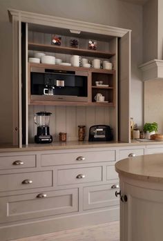 an open cabinet in the middle of a kitchen with white cupboards and drawers on both sides