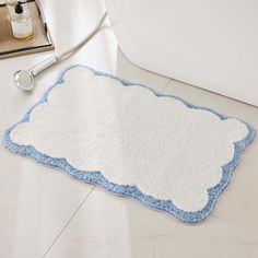 a bathroom rug with a white and blue border on the floor next to a bathtub