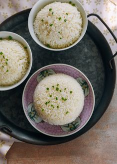 three bowls filled with rice on top of a black tray