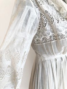 "Antique Edwardian white cotton lawn dress has eyelet lace embroidery throughout the bodice, sleeves, and around the hem. The dress has a ruffle trimmed net collar and net under bodice that has a crossover snap detail. The dress has snap and hook and eye closures at the skirt and bodice. Condition Overall excellent. There's a repair to the right sleeve, and orange stains near the seam. The front skirt has stains at the hem, the back skirt has some stains near the top of the lace, and yellowing a White Fitted Lace Dress With Lace Collar, Fitted White Lace Dress With Lace Collar, Fitted Feminine Lace Dress With Broderie Anglaise, Lace Dress With Broderie Anglaise For Garden Party, Classic Broderie Anglaise Dresses For Daywear, Classic Broderie Anglaise Dresses For Daytime, Classic Dresses With Broderie Anglaise For Daywear, White Lace Dress With Broderie Anglaise, Summer Wedding Lace Dress With Lace Cuffs