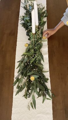 two people are placing candles on a table runner