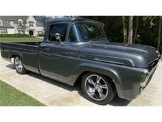 an old gray truck parked on the side of a road in front of a house