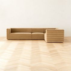 a couch sitting on top of a hard wood floor next to a white wall and wooden floor