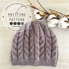 a knitted hat sitting on top of a wooden table next to cotton flowers and twine