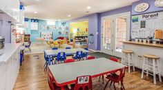 an empty classroom with tables and chairs in front of the desks that are red, blue, yellow and white