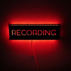 a red neon sign that says recording on it