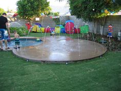 two children are playing in the backyard with water sprinkles on the ground