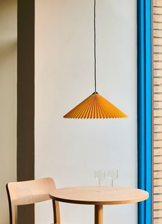 a table with two wine glasses on it next to a lamp hanging from the ceiling