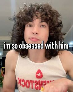 a girl with curly hair is looking at the camera and has words written on her chest