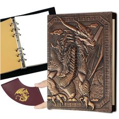 a hand holding an open book with a dragon on it